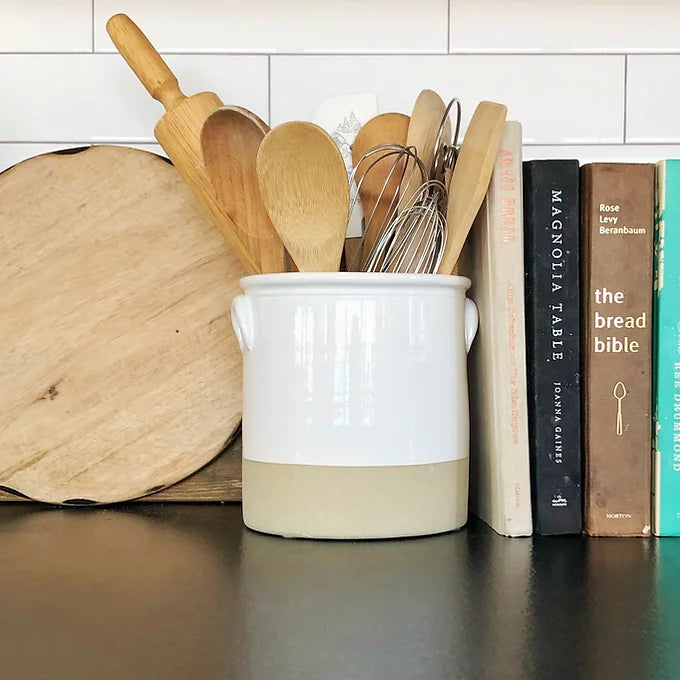 white ceramic crock with wood utensils and books